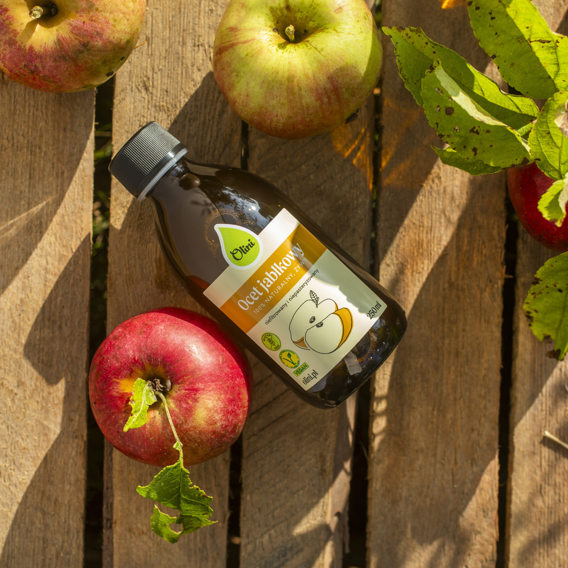 Ocet jabłkowy na stoliku w otoczeniu jabłek